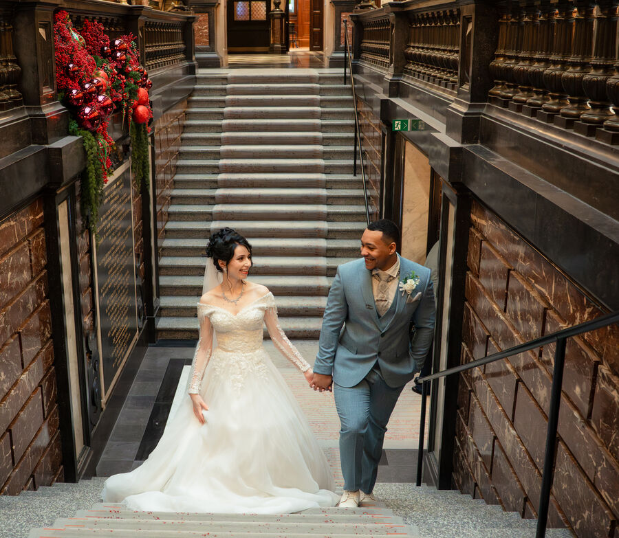 Wedding couple walking down a decorated staircase at Antwerp City Hall, Belgium