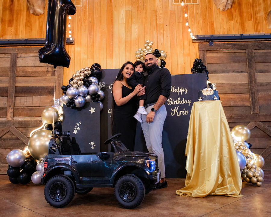 Family portrait at a first birthday party with black and gold balloon decor