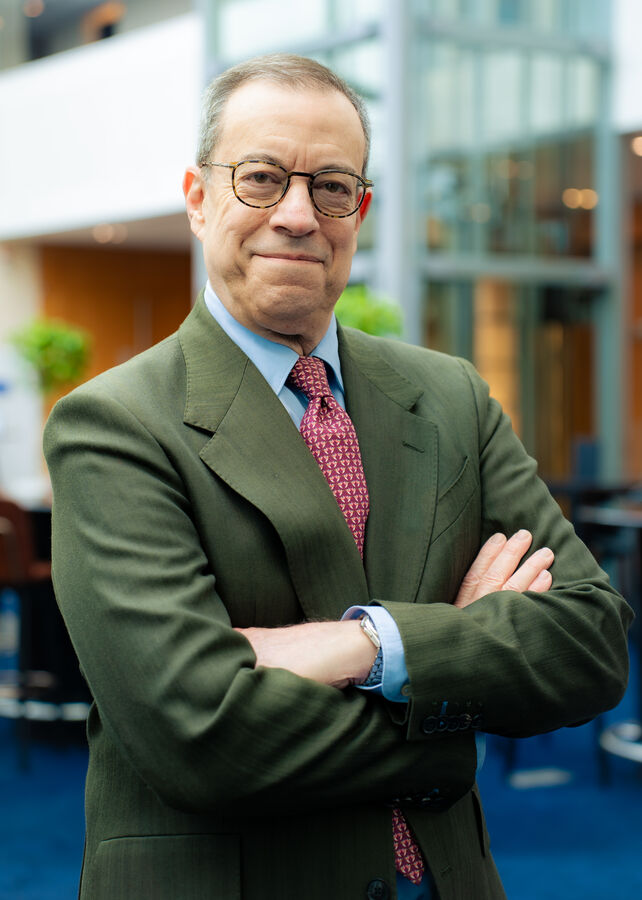 Corporate portrait of a smiling man in glasses inside a modern office building