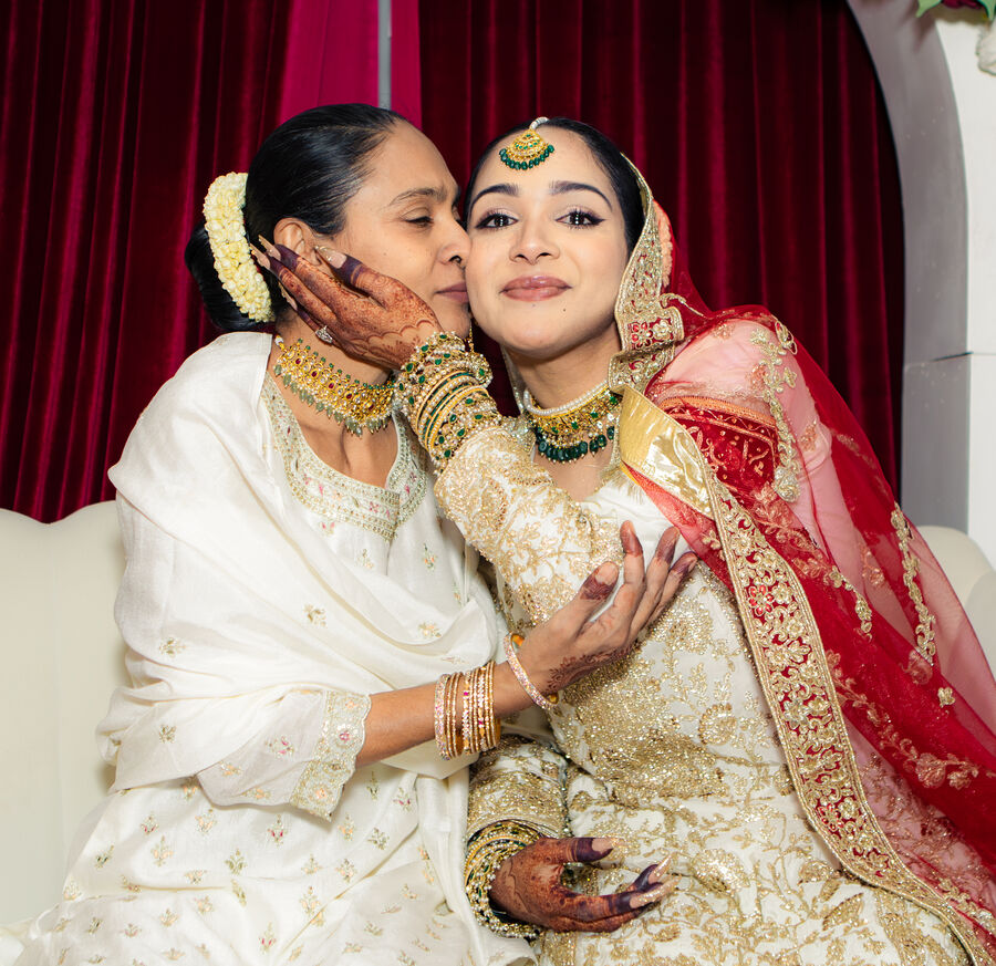 Mother kissing the bride on her cheek at a nikkah ceremony