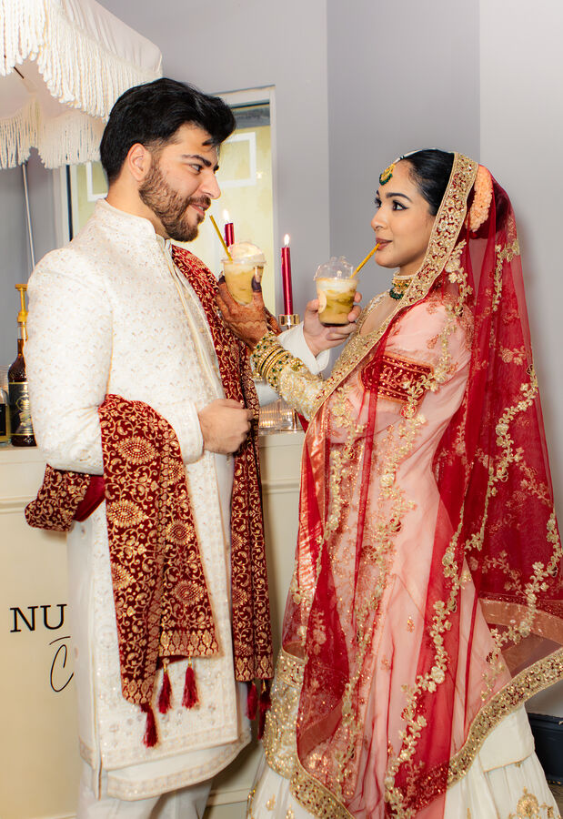 Bride and groom in traditional dress sharing drinks at their wedding