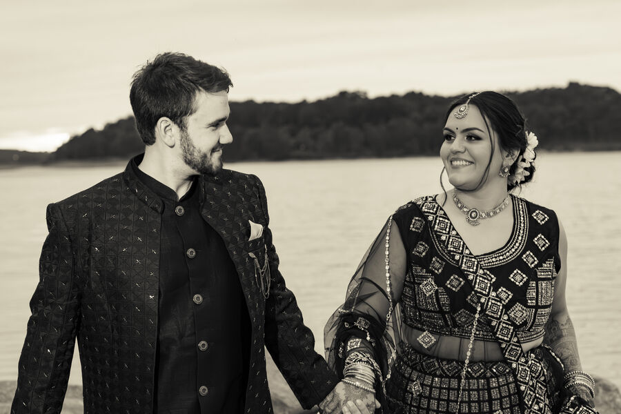 Sepia portrait of a wedding couple holding hands by a lake