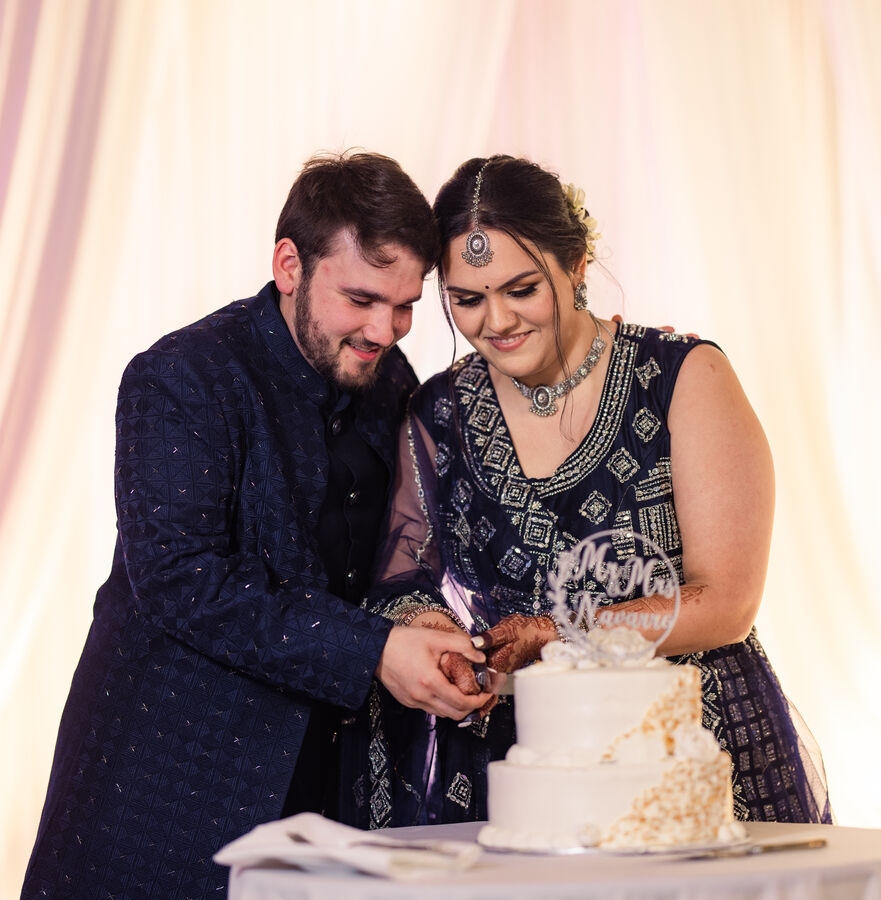 Bride and groom in navy cutting their wedding cake together